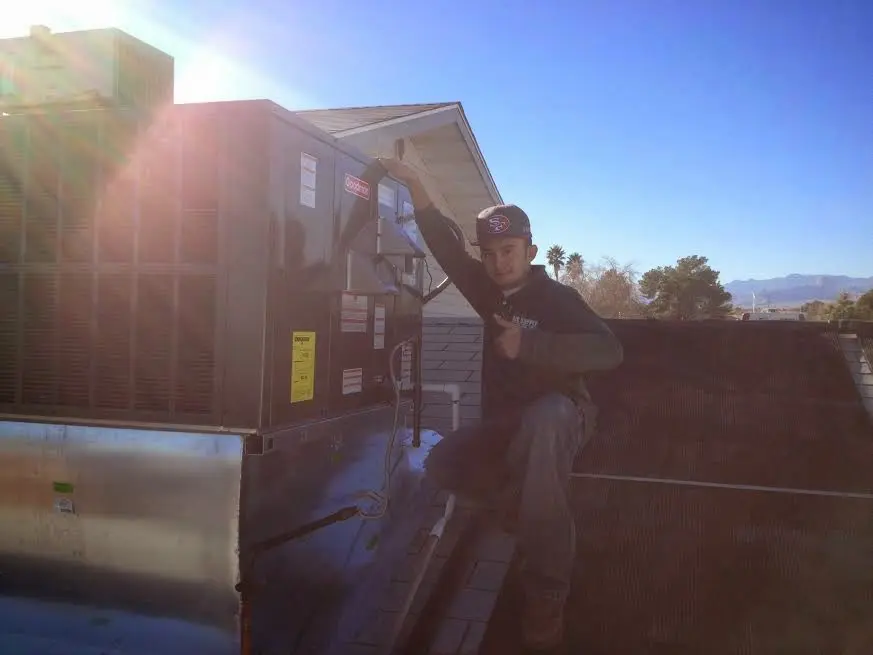 HVAC technician performing AC Tune-Up on a rooftop unit in Holmen